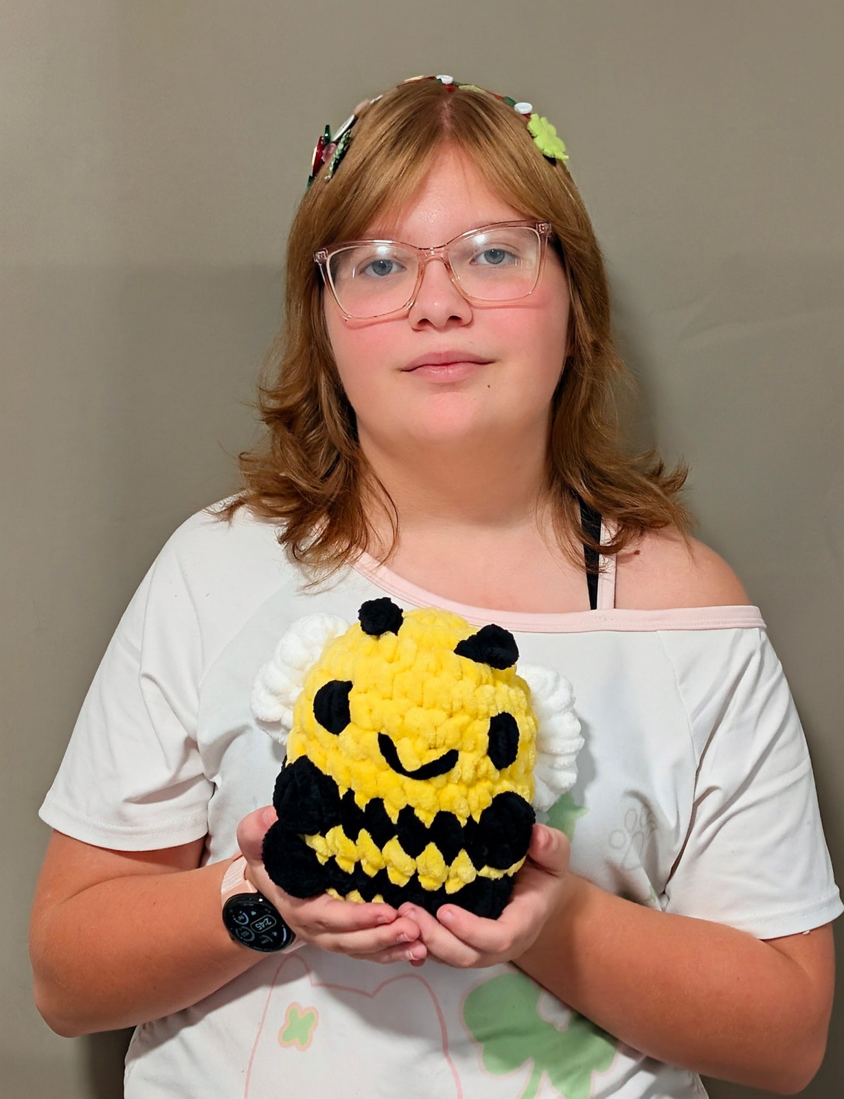Flora holding the yellow and black crochet sitting bee plushie she made