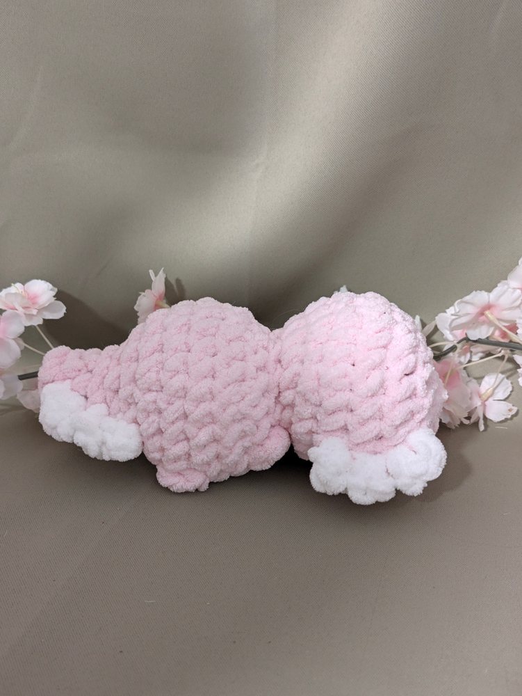 Back view of the chunky crochet axolotl plushie lying on its side, showing its white feet