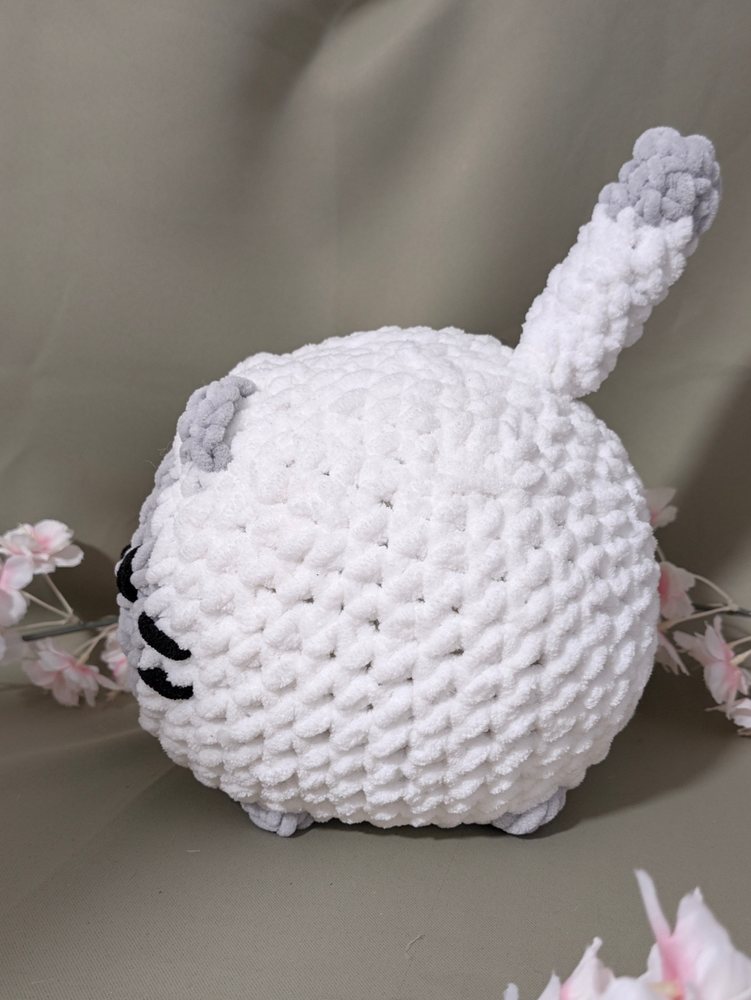 Side view of the white crochet loaf cat plushie with its tail sticking up