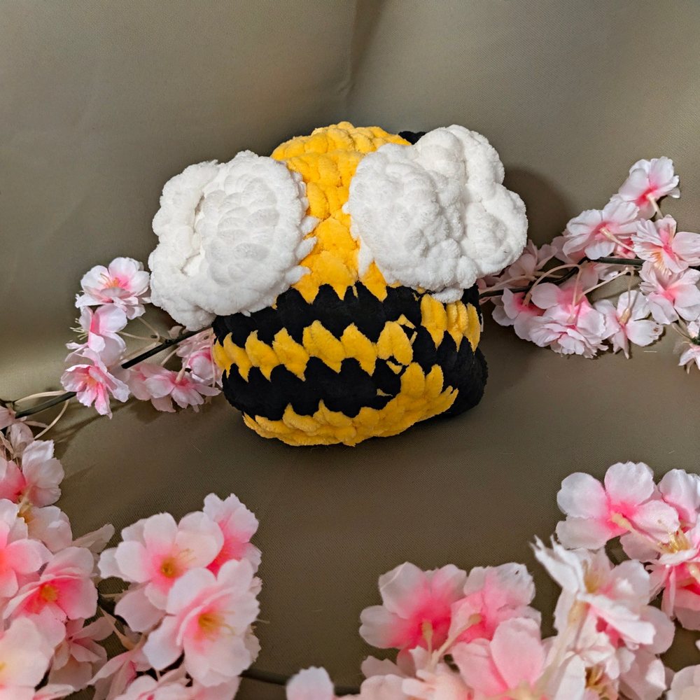 Back view of the yellow and black crochet sitting bee plushie showing its white wings