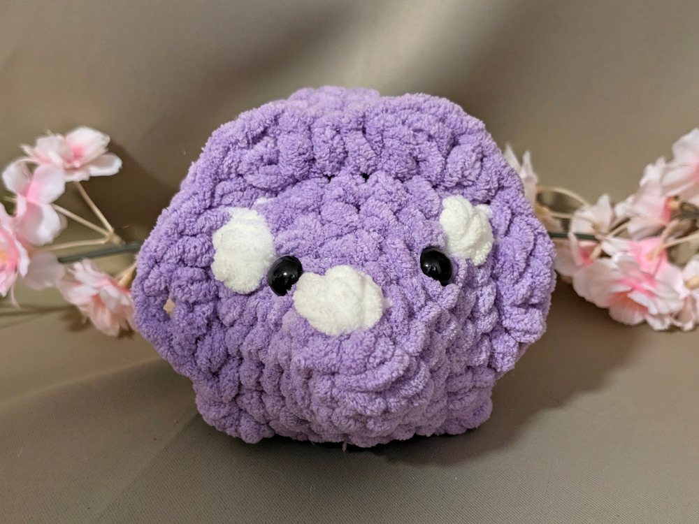 Purple crochet triceratops plushie with white horn and brow spots